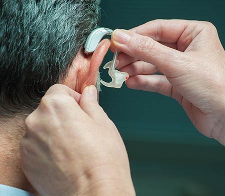 Doctor Putting Hearing Aid on Man